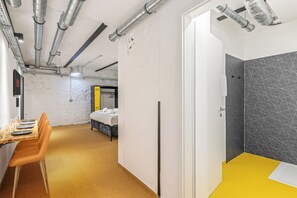 A hotel room with a bed, a bathroom, and a dining area with a table and chairs. - Compact Studio | Karmelitermarkt | Self-Recording (Wien)