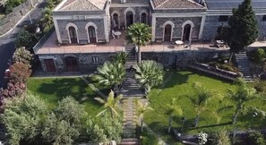 A large building with a courtyard, a staircase leading to the entrance, and palm trees.