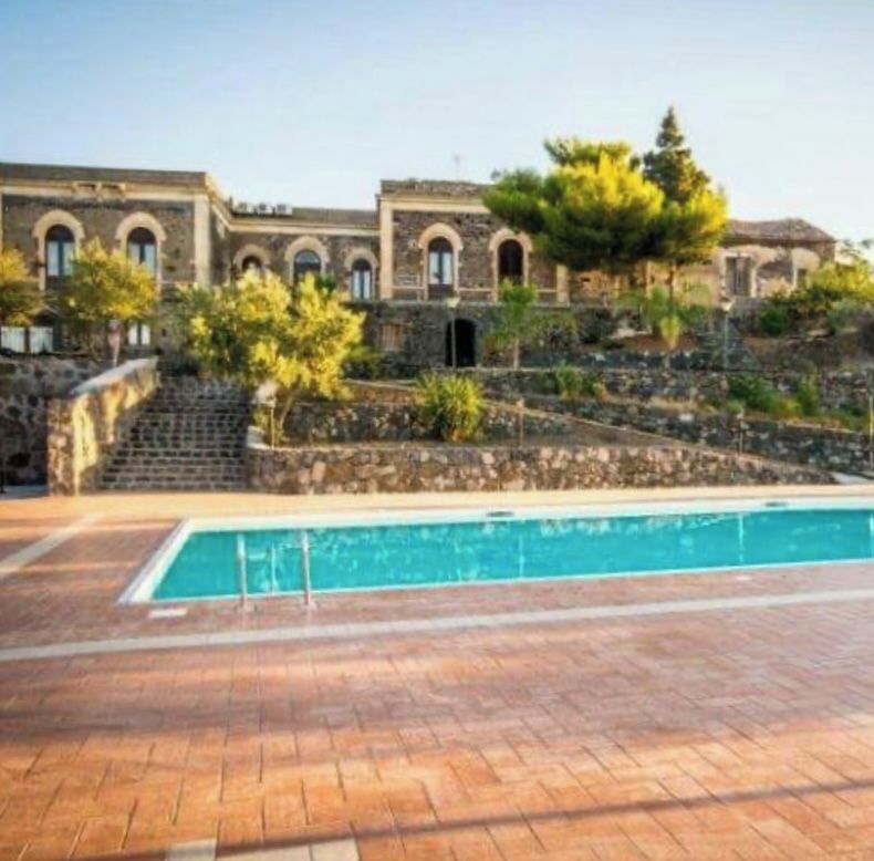Una zona de piscina con un sendero de piedra que conduce a un edificio con ventanas arqueadas.