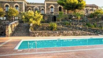 Una zona de piscina con un sendero de piedra que conduce a un edificio con ventanas arqueadas.