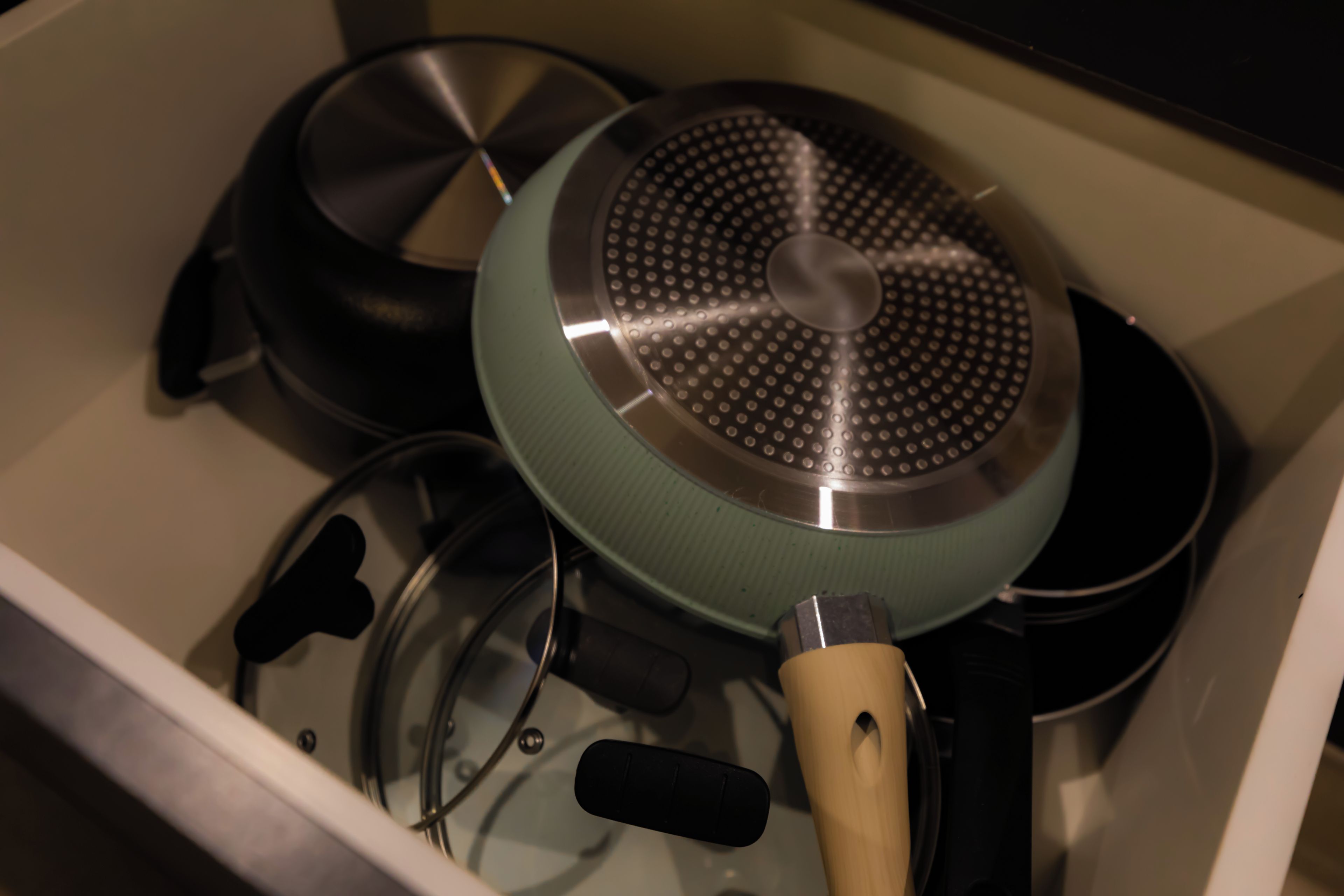 Un tiroir de cuisine contenant divers ustensiles de cuisine, notamment des casseroles et des poêles.