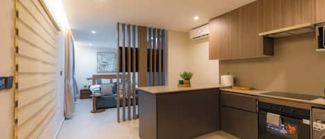 A modern kitchen with a built-in oven, a dishwasher, and a dining area with a sofa and table.