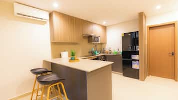 A modern kitchen with a central island, bar stools, a microwave, and a refrigerator.