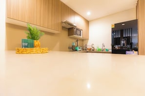 A modern kitchen with wooden cabinets, a microwave, and a water dispenser. - Beaufort Ridge (Accra)