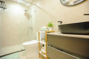 Ein modernes Badezimmer mit Duschkabine aus Glas, einer weißen Toilette und einem Waschtisch.