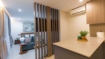 A modern hotel room with a kitchenette, a dining area, and a living space.