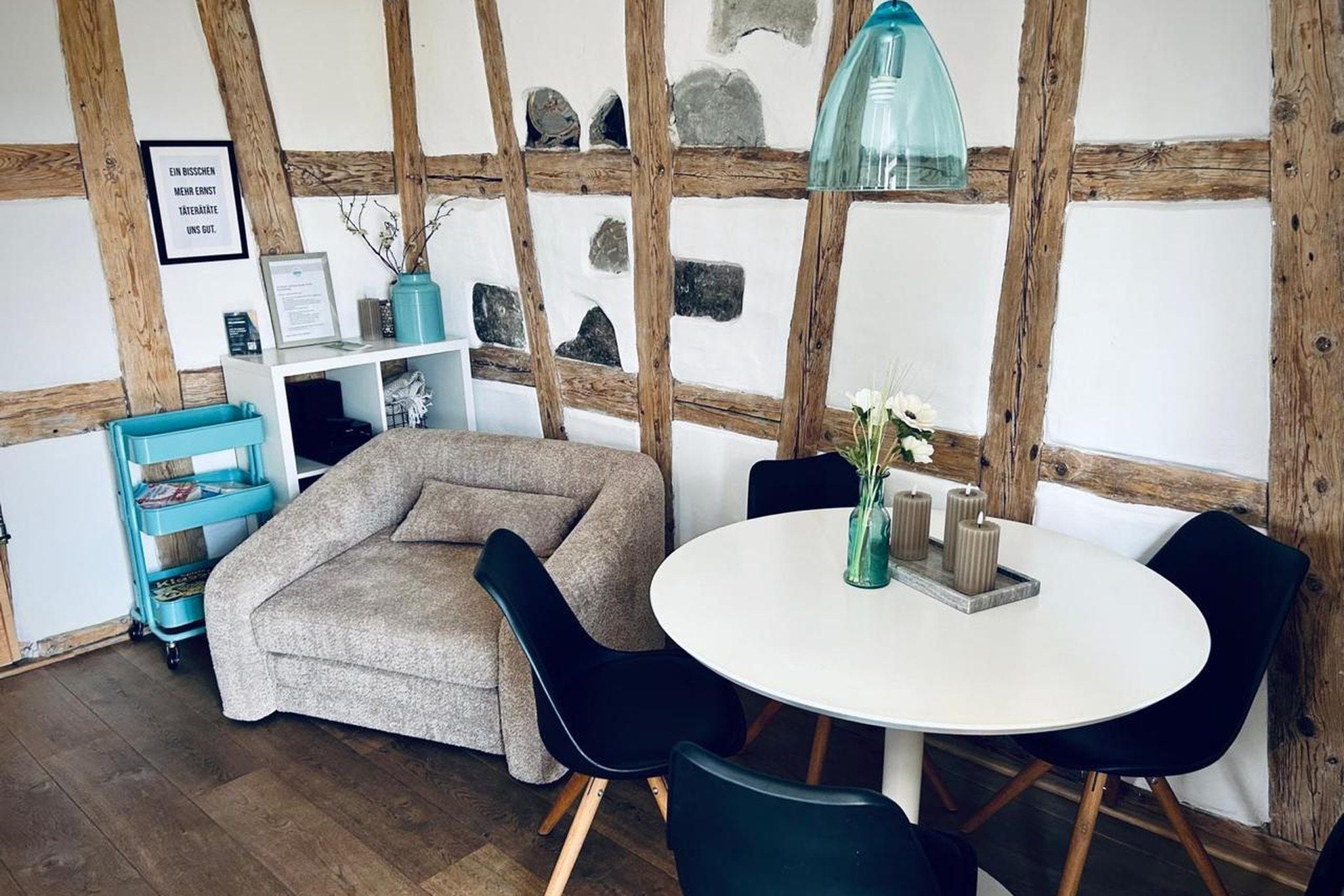 Una habitación acogedora con una mesa redonda, sillas, un sofá y una estructura de techo de madera.