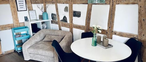 Una habitación acogedora con una mesa redonda, sillas, un sofá y una estructura de techo de madera.