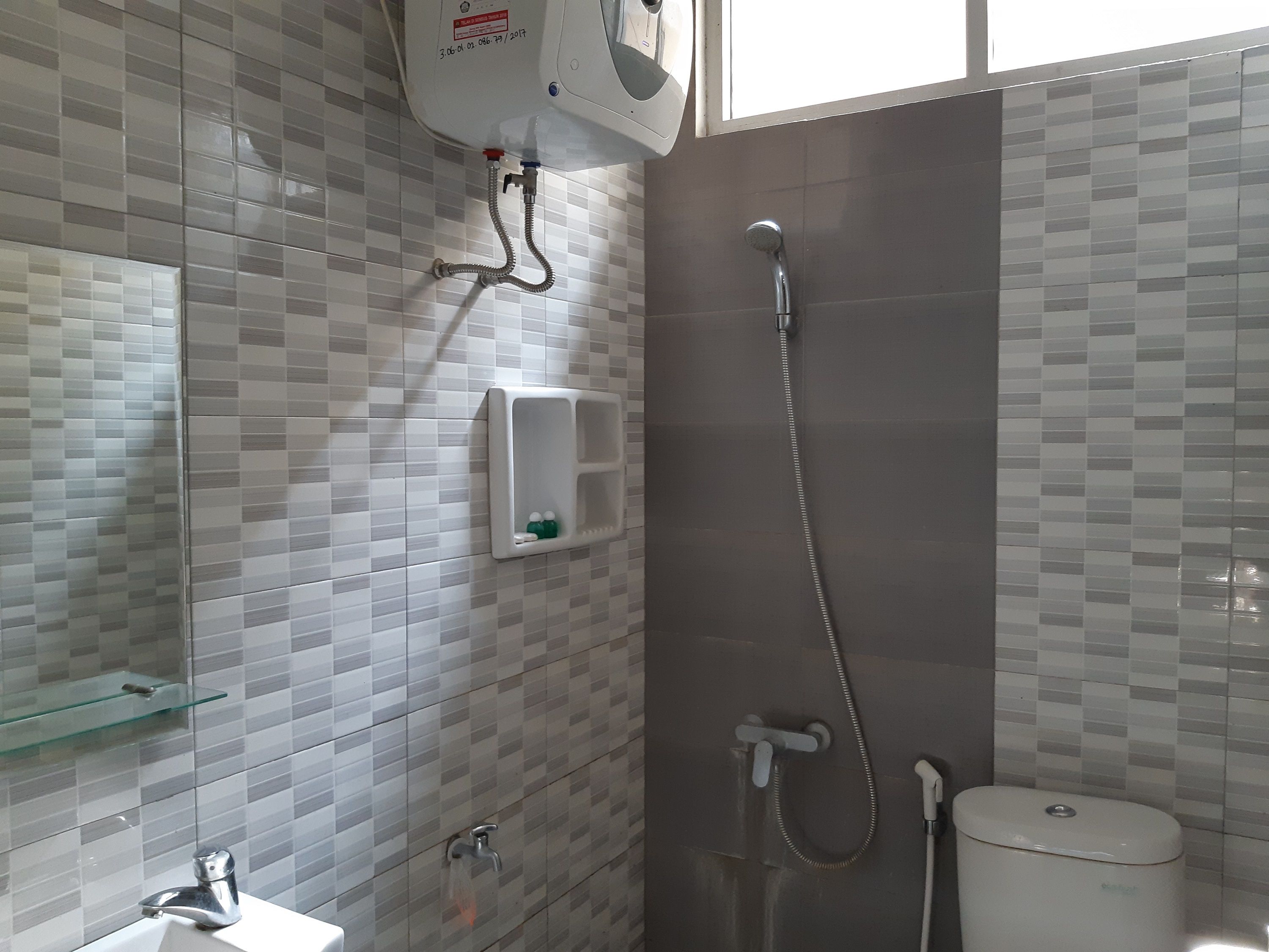 Ein Badezimmer mit Dusche, Toilette, Waschbecken und Ablagefläche aus Glas.