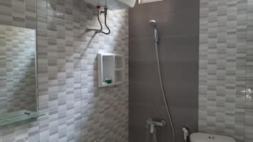 Ein Badezimmer mit Dusche, Toilette, Waschbecken und Ablagefläche aus Glas.