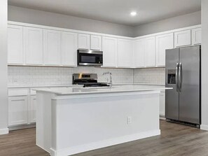 A modern kitchen with white cabinetry, a stainless steel refrigerator, and a built-in microwave. - Modern 4BR Home • Office • Patio • 3 Full Baths (McKinney)