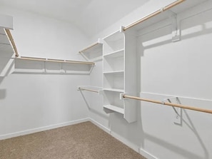 A room with white walls, a beige carpet, and built-in wooden shelves with metal brackets. - Modern 4BR Home • Office • Patio • 3 Full Baths (McKinney)