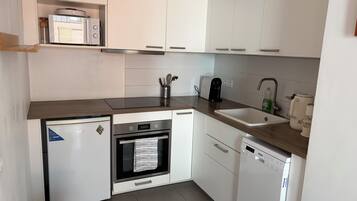 A compact kitchen with a built-in oven, a coffee maker, and a dishwasher.
