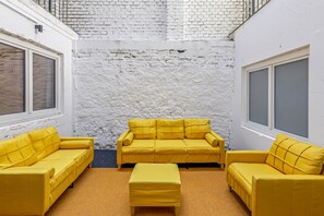 A room with a white brick wall, a yellow sofa set, and a window. - Studio with a private terrace | Karmelitermarkt (Wien)