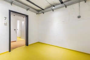 A hallway with a yellow floor, white walls, and a door leading to another room. - Studio with a private terrace | Karmelitermarkt (Wien)
