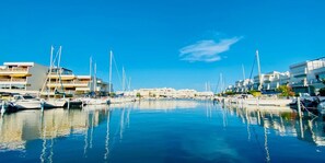 Ein Yachthafen mit vertäuten Booten, Gebäuden mit Balkonen und einem strahlend blauen Himmel.