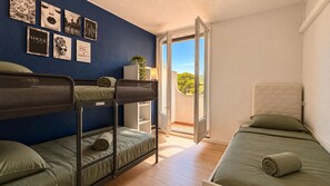Ein Zimmer mit Etagenbetten, einem Balkon und Blick auf Grünflächen.