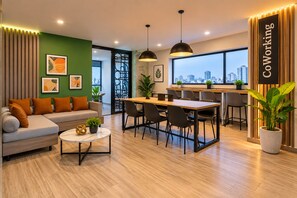 A modern interior with a sofa, dining table, and chairs, a city view, and a sign reading 'Coworking'. - Estrella Luxury | Pool, Gym, and Coworking Space in Pueblo Libre (Lima)