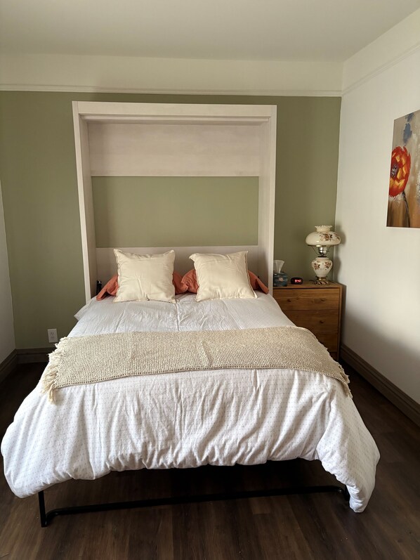 A bed with a white and beige patterned bedspread, two pillows, and a headboard.