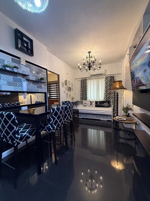 Una sala moderna con un sofá estampado en blanco y negro, una araña y una cama con cabecera estampada.