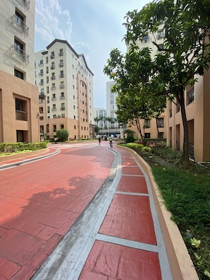 A residential area with multi-story buildings, a curved red pathway, and greenery. -  1-bedroom condo with pool walking distance to NAIA Terminal 3 Pasay City (Pasay City)