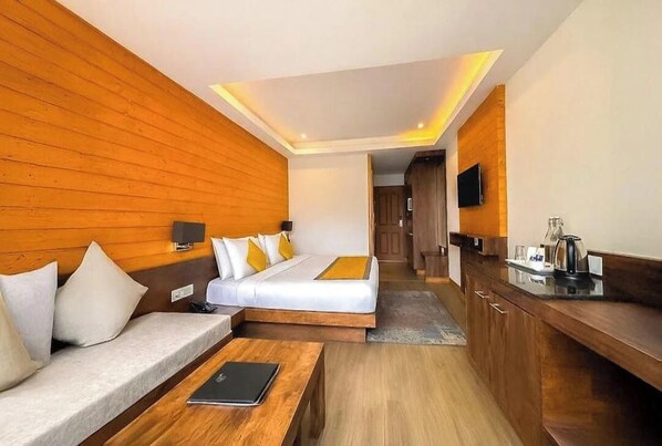 A hotel room with a bed, a sofa, a desk, and a television. - Sanderling Mall Road (Darjeeling)