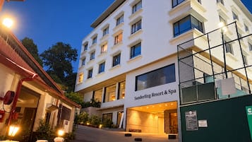 Een meerlaags hotel met een moderne gevel, een duidelijke ingang en een bord waarop staat dat het een resort en spa is.