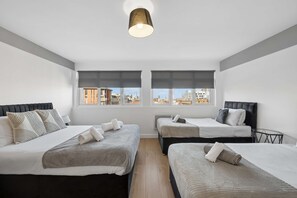 A hotel room with two beds, a ceiling light, and windows with city views. - Sleek Spacious 2BR Apartment in Liverpool (Liverpool)