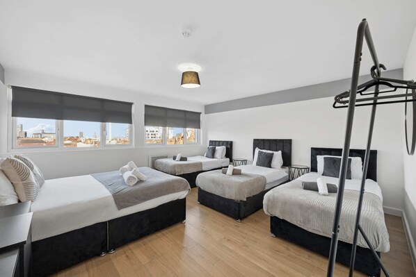 A hotel room with four beds, a ceiling light, and a view of the cityscape. - Sleek Spacious 2BR Apartment in Liverpool (Liverpool)