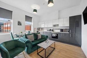 A modern kitchen with grey cabinets, a black refrigerator, and a microwave. - Stylish 2BR Liverpool City Centre Apartment (Liverpool)