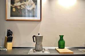 A kitchen counter with a coffee maker, a green vase, and a knife block. - The Miracle House (Napoli)