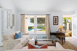 A living room with a sofa, a glass coffee table, and a view of a swimming pool through large windows. - Raithbury Hill House (Stellenbosch)