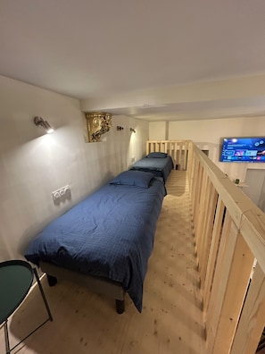 A room with two beds, a wooden staircase, and a television on the wall. - The Alsatian Inn - 14 guests (Strasbourg)
