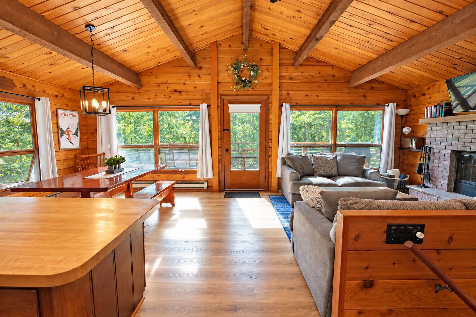 Una cabaña amplia con interior de madera, un comedor, un sofá y una chimenea.