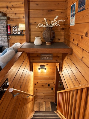 Een houten trap met een bord waarop 'The Mountains Happy Place' staat en een decoratieve vaas met takken.