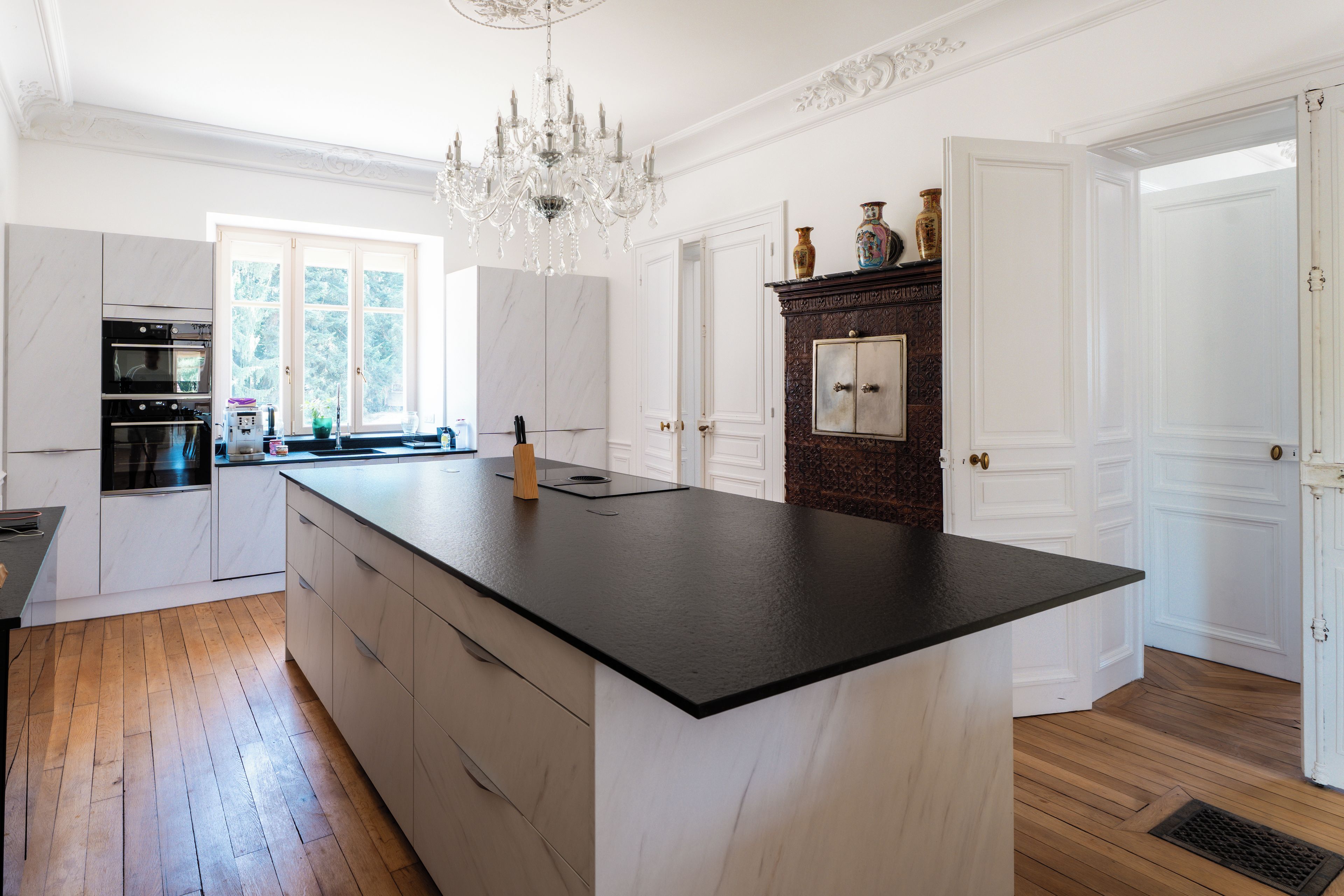 Een keuken met een groot eiland, een ingebouwde oven en een kroonluchter.