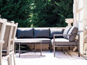 Een buitenruimte met een zithoek, inclusief een bank, stoelen, een tafel en een potplant.