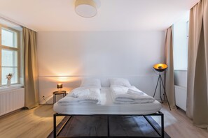 Una camera d'albergo con un letto, una lampada da comodino e una lampada da terra.
