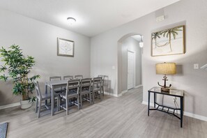 A dining area with a table and chairs, a potted plant, and a framed picture on the wall. - 4-bedroom House in Regal Oaks Near Disney (Kissimmee)