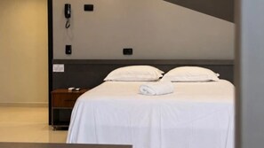 Habitación de hotel con cama, mesita de noche y teléfono en la pared.