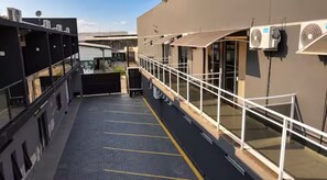 Una terraza en la azotea con barandilla metálica, zona cubierta y equipos de aire acondicionado.