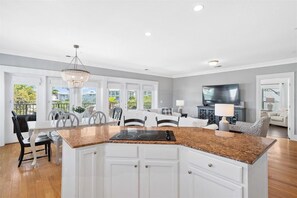 A modern kitchen with a granite countertop, white cabinetry, and a built-in stove. - Sea Sanctuary (Panama City Beach)