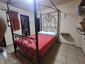 A single bed with a metal frame and a red bedspread in a room with tiled flooring. - Hotel Antigua Encomienda (ATLIXCO)