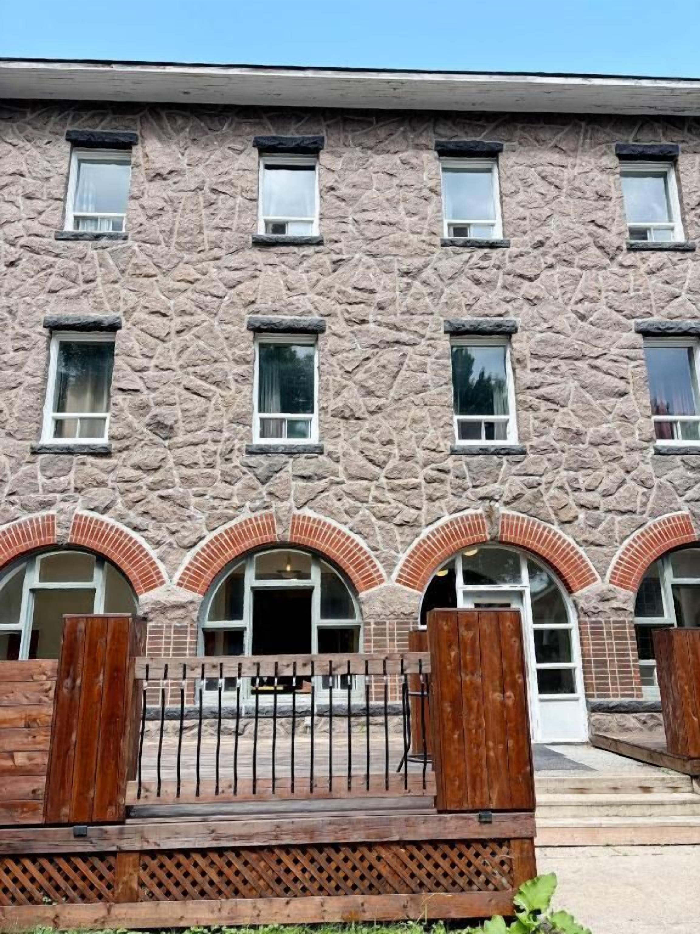 A building with a stone facade, multiple windows, and a wooden fence in the foreground.