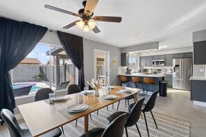 A modern kitchen with a central island, dining area with a table set for four, and a ceiling fan. - The Hermosa House - Tempe Getaway- Relax (Tempe)