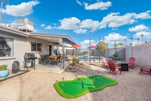 A backyard with a pool, patio furniture, and a miniature golf setup. - The Hermosa House - Tempe Getaway- Relax (Tempe)