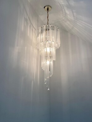 Ein Chandelier mit mehreren Etagen aus klarem Kristall, das an einer Kette von der Decke hängt.