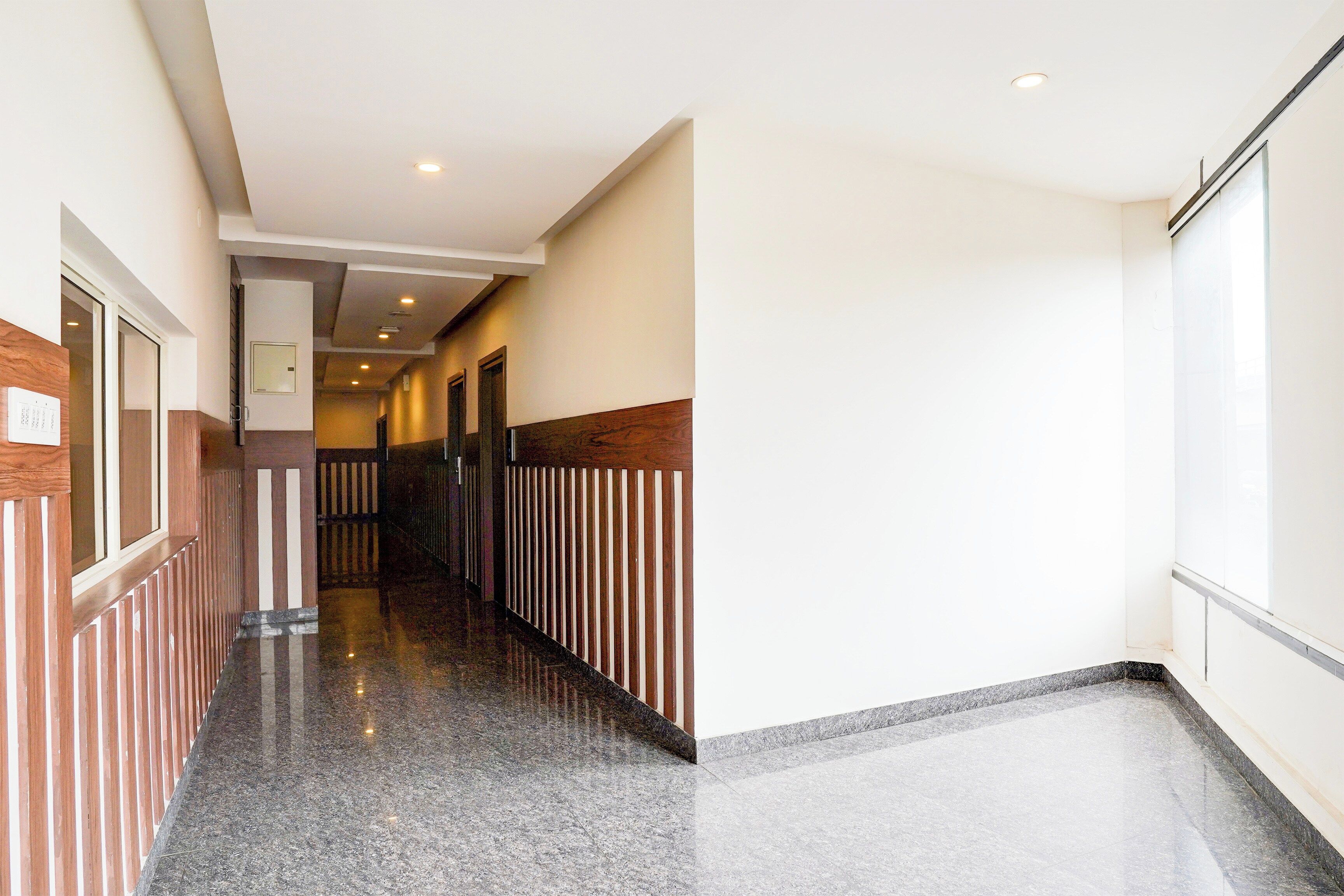 A hotel corridor with a polished floor, wooden paneling on the walls, and a series of doors leading to rooms.
