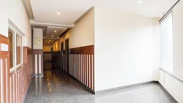 A hotel corridor with a polished floor, wooden paneling on the walls, and a series of doors leading to rooms.