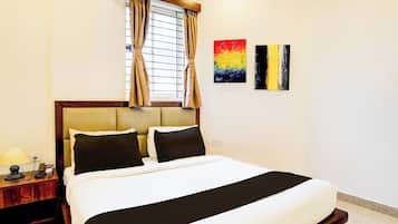 A hotel room with a bed, a nightstand, a lamp, and two paintings on the wall.